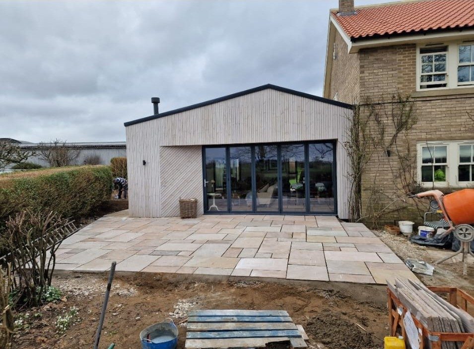 Timber-clad garden room extension with sandstone patio